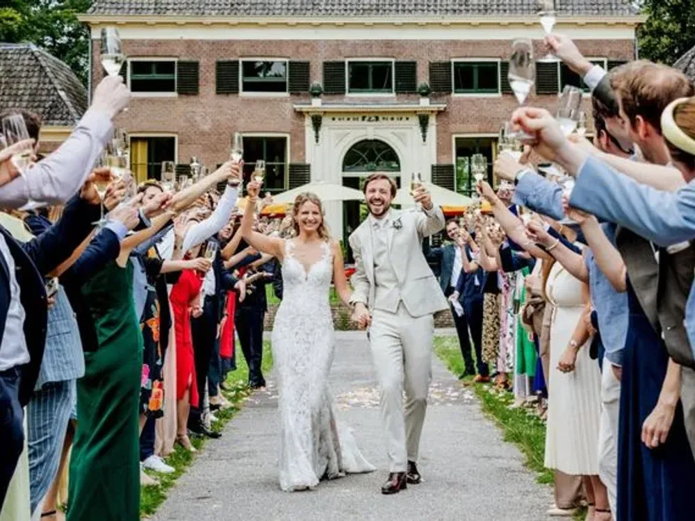 Bruidspaar loopt door een erehaag van gasten met champagne
